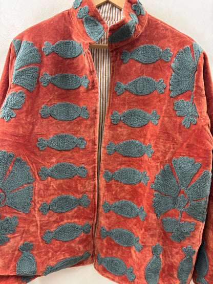 Red jacket with blue fish patterns on a hanger against a white background