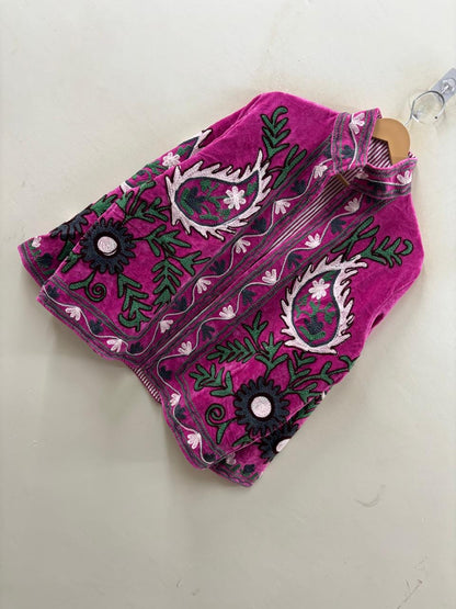 Embroidered pink pouch with black and white patterns on a light gray background