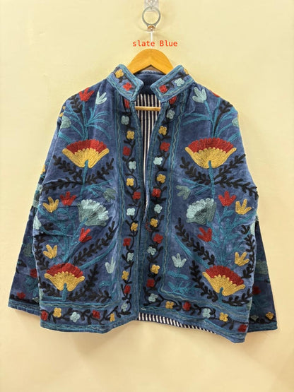 Blue embroidered jacket with colorful floral patterns on a yellow background