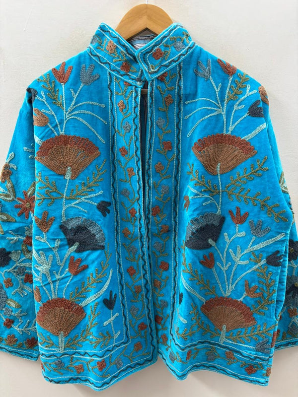 Blue embroidered garment on a hanger against a white background
