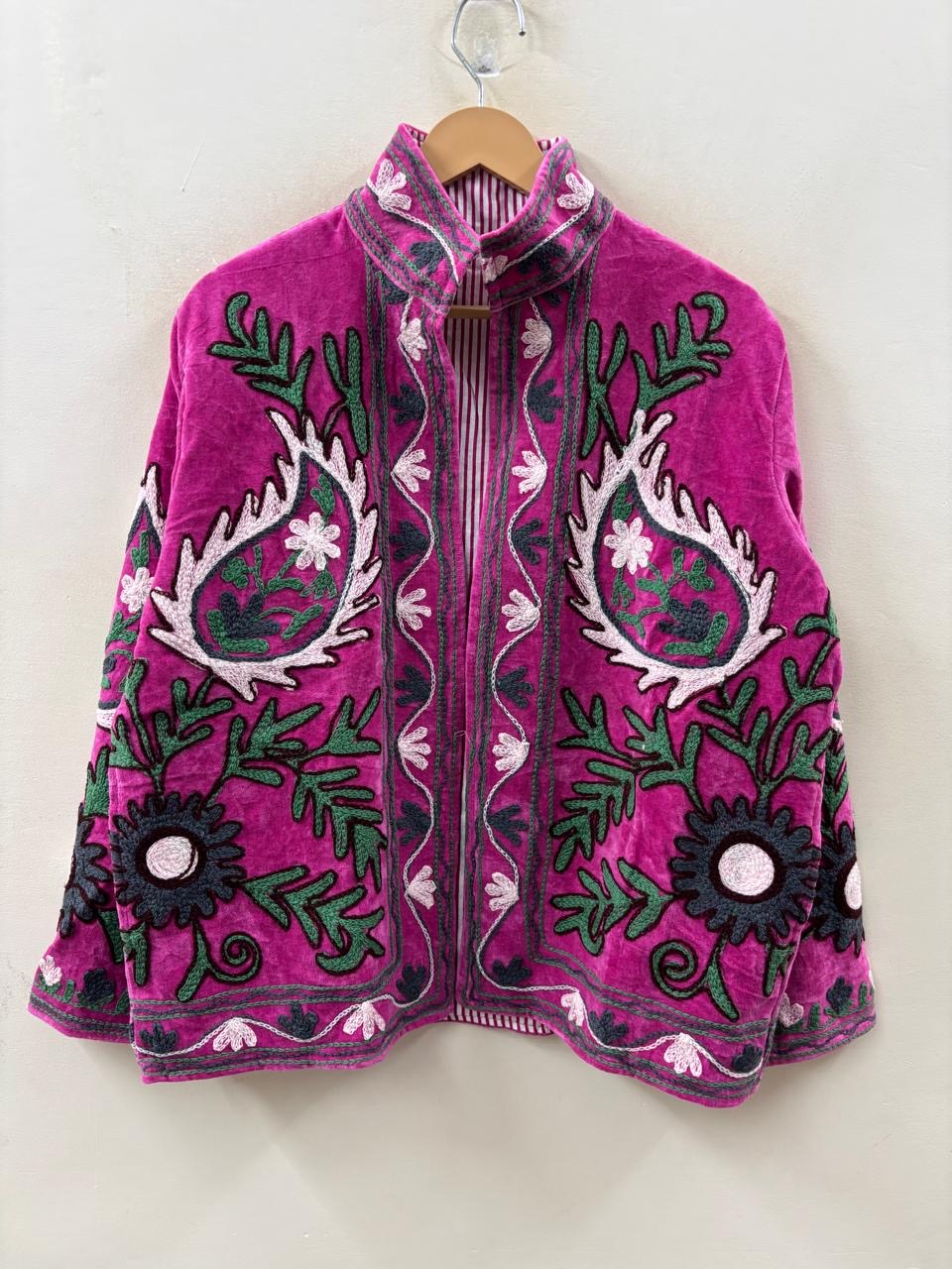 Pink embroidered jacket with green and black patterns on a white background