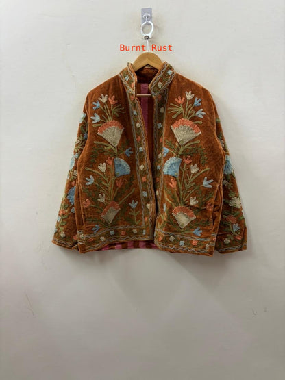 Embroidered jacket with floral patterns on a hanger against a white background