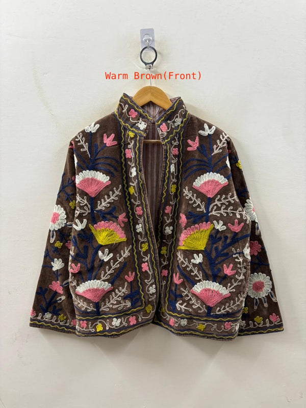 Embroidered jacket with floral patterns on a hanger against a white background