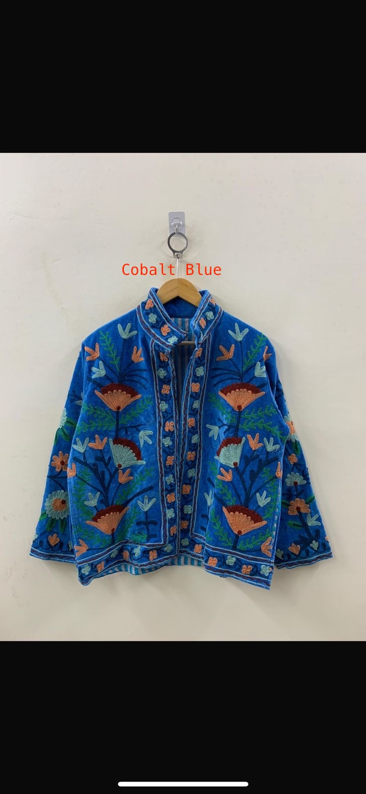 Blue embroidered jacket on a hanger against a white wall with 'Cobalt Blue' label.
