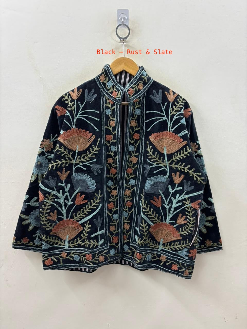 Floral embroidered jacket on a hanger against a white background
