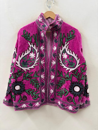 Pink embroidered jacket with green and black patterns on a white background